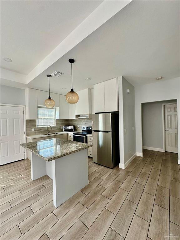 kitchen featuring a center island, sink, appliances with stainless steel finishes, light hardwood / wood-style floors, and white cabinetry