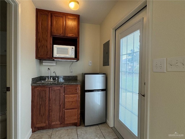 kitchen featuring electric panel, stainless steel fridge, sink, and light tile patterned floors