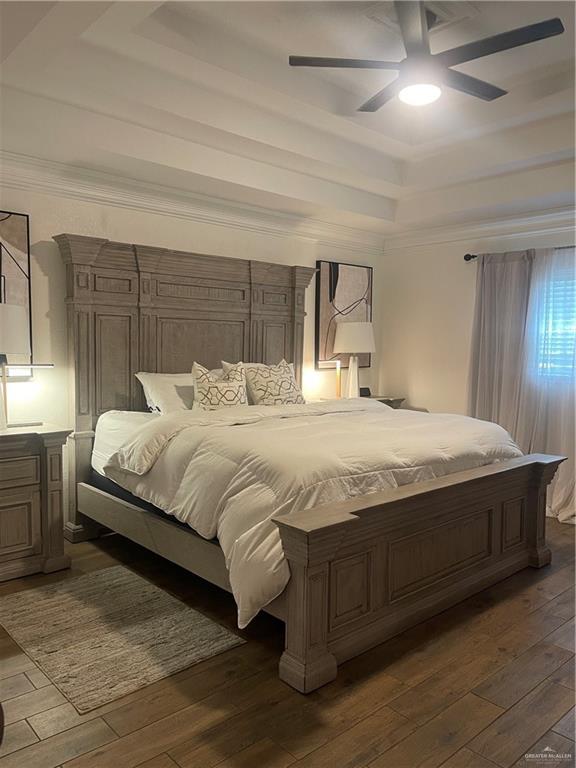 bedroom featuring ornamental molding, a raised ceiling, dark wood finished floors, and ceiling fan