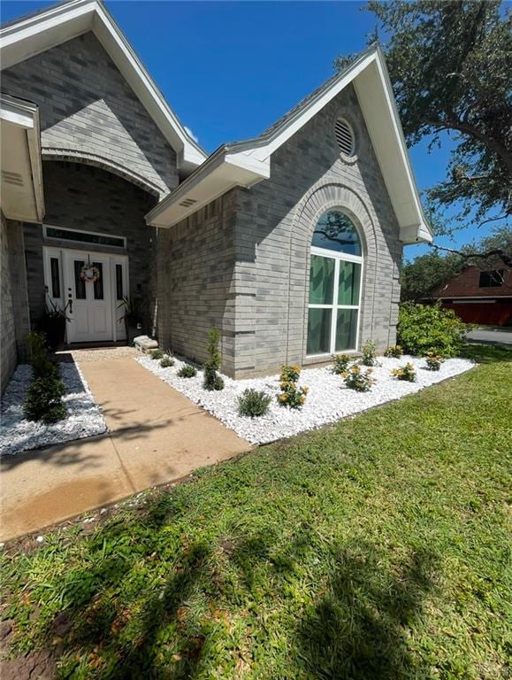 view of home's exterior featuring brick siding and a lawn