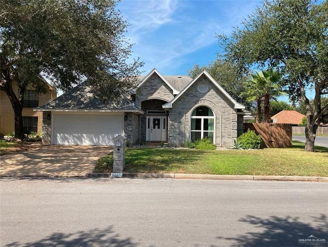 view of front of property featuring a garage, driveway, fence, a front yard, and brick siding