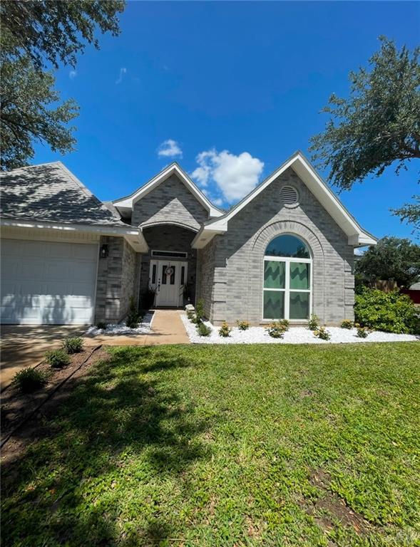 ranch-style house with a garage, a front lawn, and brick siding