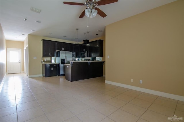 kitchen featuring a kitchen breakfast bar, open floor plan, light countertops, dark cabinetry, and stainless steel fridge