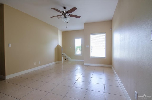 unfurnished room with light tile patterned flooring, ceiling fan, baseboards, and stairs