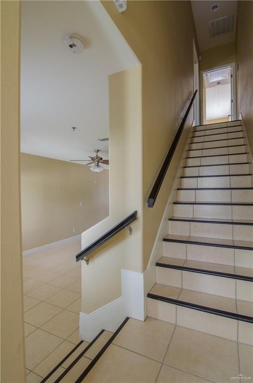 stairway featuring a ceiling fan, visible vents, baseboards, and tile patterned floors