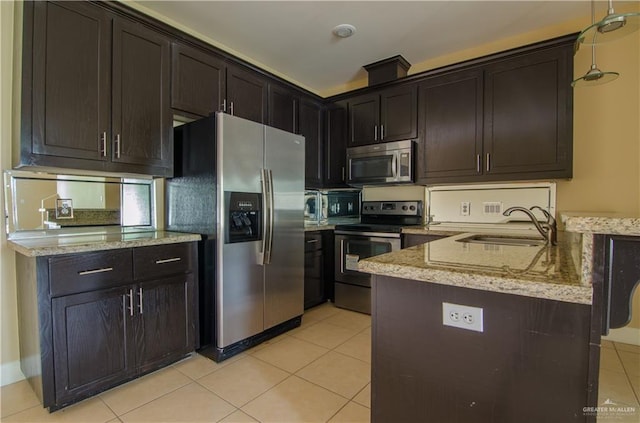 kitchen with stainless steel appliances, light tile patterned flooring, a sink, light stone countertops, and a peninsula