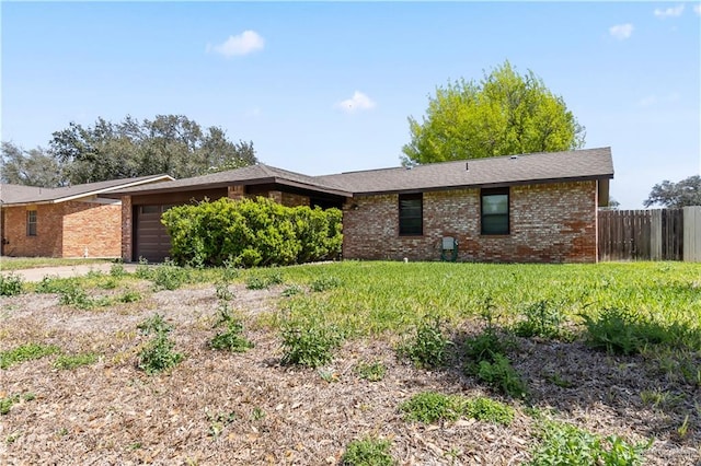 view of side of property with a garage, brick siding, and fence