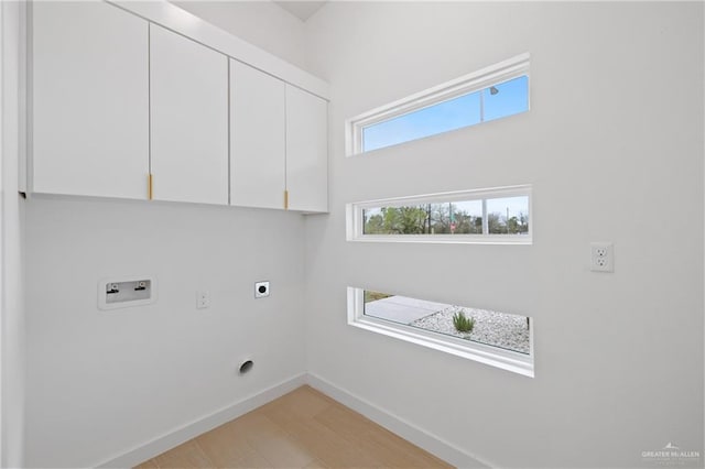 clothes washing area with hookup for a washing machine, hookup for an electric dryer, cabinet space, and baseboards