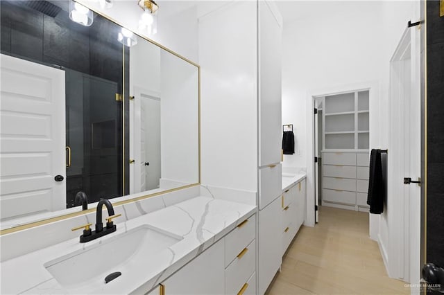 full bath with a walk in closet, wood finished floors, and vanity