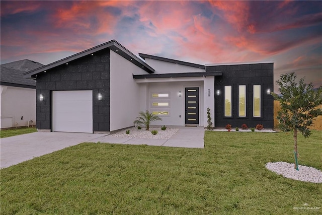 contemporary home with a front lawn, concrete driveway, an attached garage, and stucco siding