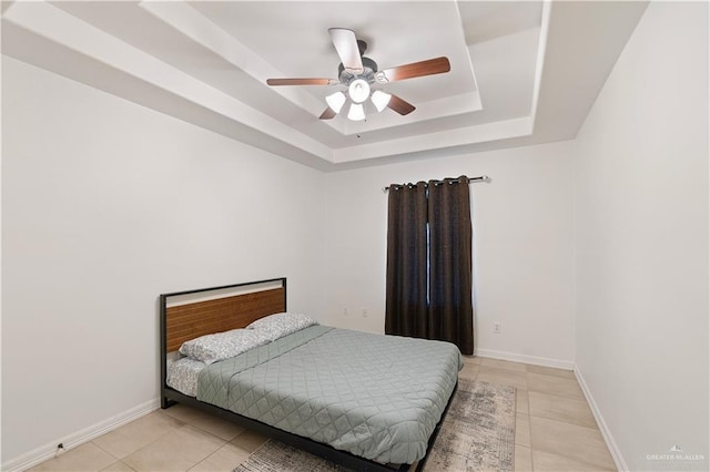 bedroom featuring ceiling fan, light tile patterned floors, and a tray ceiling