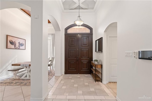 tiled entryway with beam ceiling, a towering ceiling, crown molding, and coffered ceiling