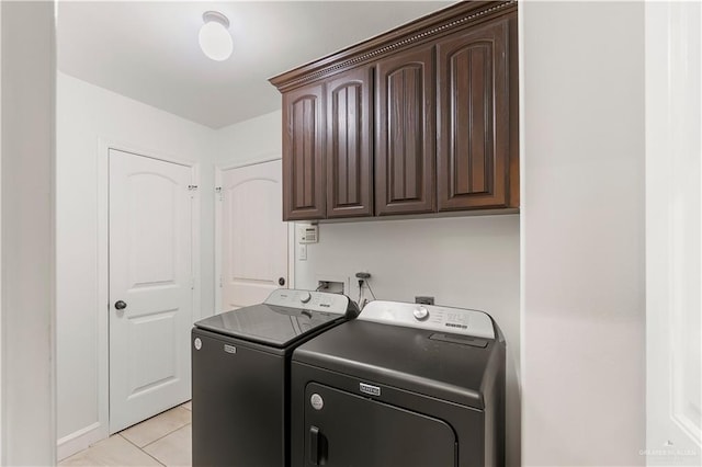 laundry room featuring washer and dryer, cabinets, and light tile patterned floors