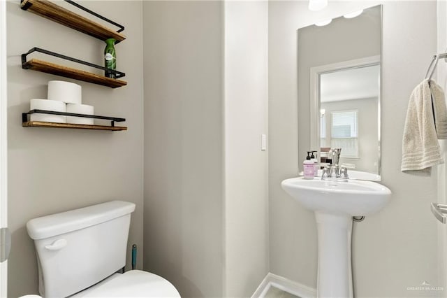 bathroom with a sink, baseboards, and toilet