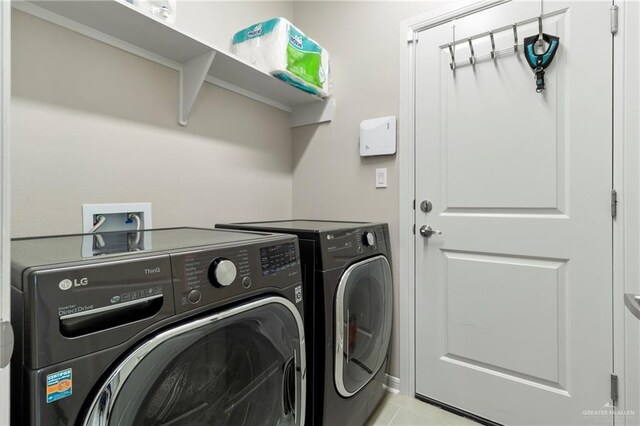 clothes washing area with laundry area, light tile patterned flooring, and washing machine and dryer