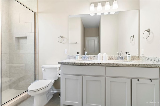 bathroom featuring double vanity, a shower stall, toilet, and a sink