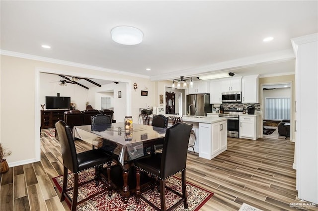 dining room with baseboards, ornamental molding, wood finish floors, and recessed lighting