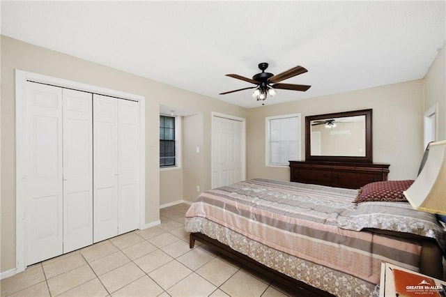 bedroom with multiple closets, a ceiling fan, baseboards, and light tile patterned floors