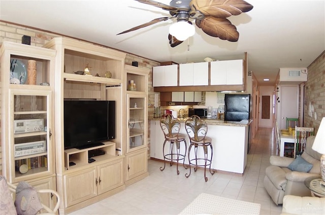 living area featuring visible vents, a ceiling fan, and brick wall