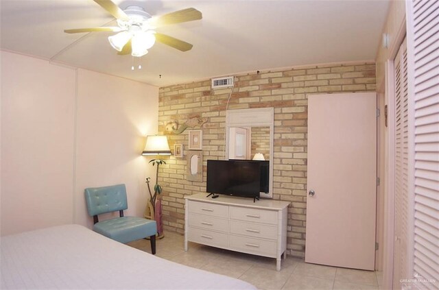 bedroom with brick wall, a ceiling fan, visible vents, and light tile patterned floors