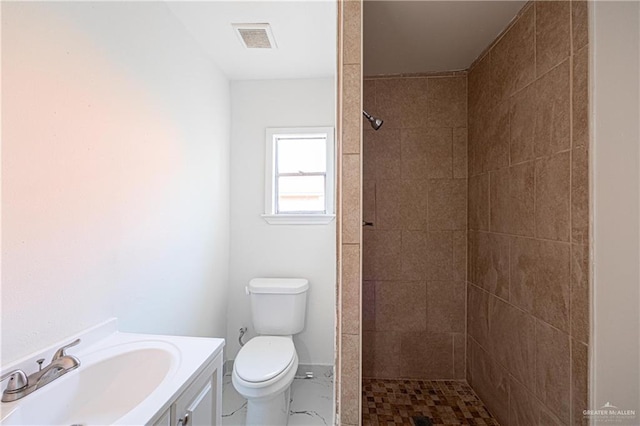 full bath with vanity, toilet, baseboards, visible vents, and tiled shower