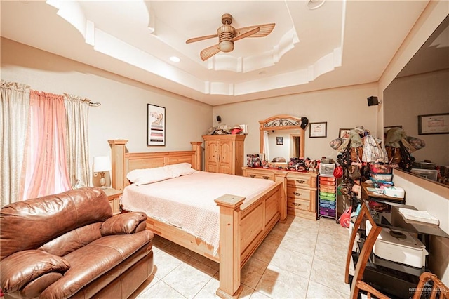 bedroom featuring ceiling fan, light tile patterned floors, and a raised ceiling