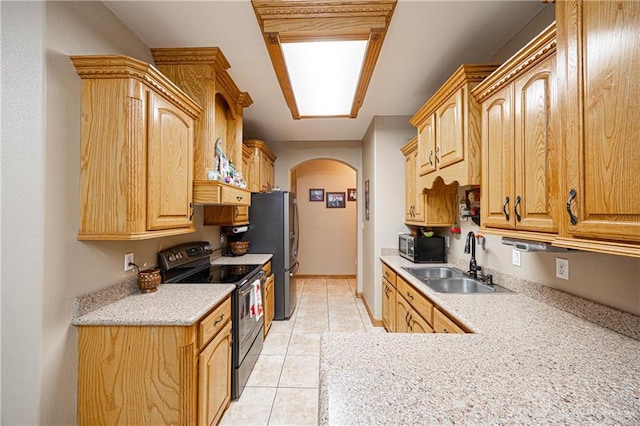 kitchen with a sink, light countertops, arched walkways, range with electric cooktop, and light tile patterned floors