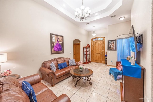 living room featuring arched walkways, light tile patterned floors, a raised ceiling, an inviting chandelier, and a high ceiling