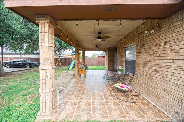 view of patio with a playground, fence, and ceiling fan