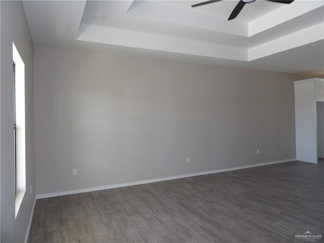 unfurnished room featuring dark hardwood / wood-style floors, a raised ceiling, and ceiling fan