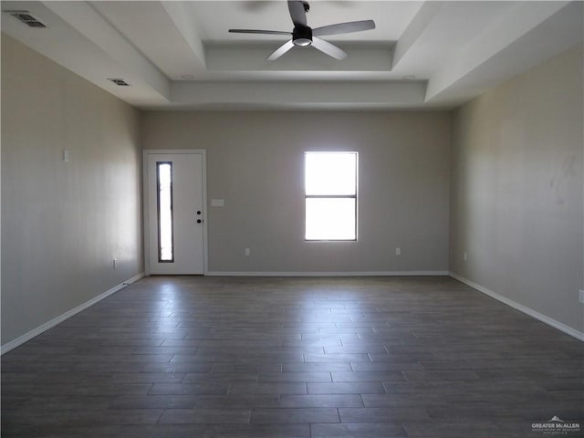 empty room featuring ceiling fan, a healthy amount of sunlight, and a tray ceiling