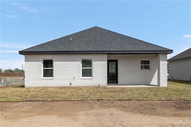 back of house with brick siding and roof with shingles