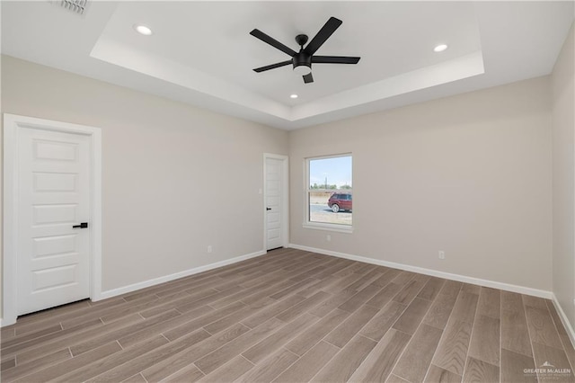 empty room featuring light wood-style flooring and a tray ceiling