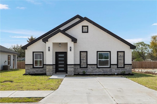 view of front of home with stone siding, fence, a front lawn, and cooling unit