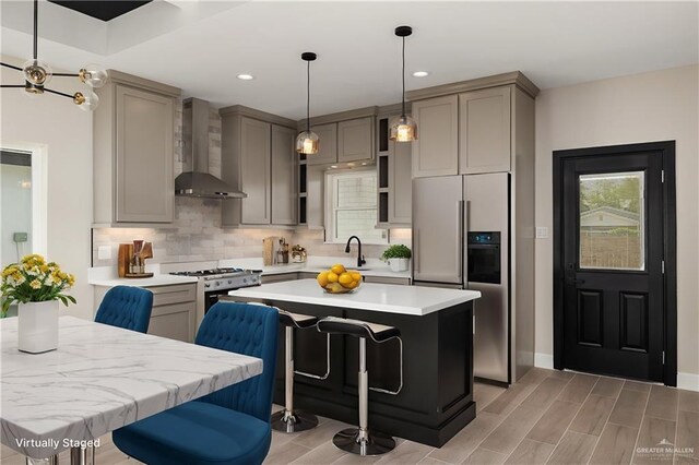 kitchen with white gas stove, gray cabinetry, high end fridge, backsplash, and wall chimney exhaust hood