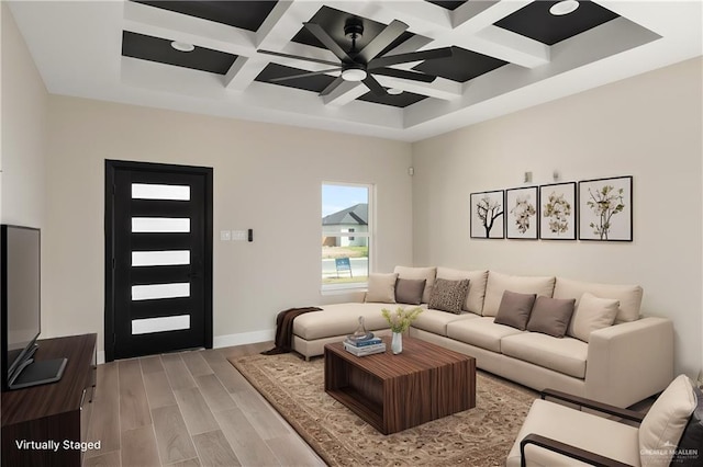 living area with ceiling fan, coffered ceiling, baseboards, light wood-type flooring, and beamed ceiling