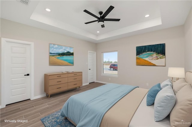 bedroom with wood tiled floor, baseboards, and a raised ceiling