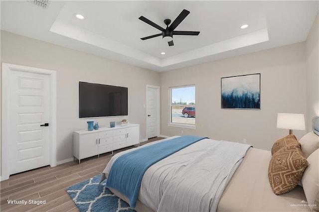 bedroom featuring recessed lighting, a raised ceiling, and wood tiled floor