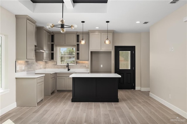 kitchen with backsplash, gray cabinets, a sink, and a center island