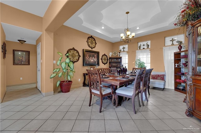 tiled dining space featuring a chandelier and a raised ceiling