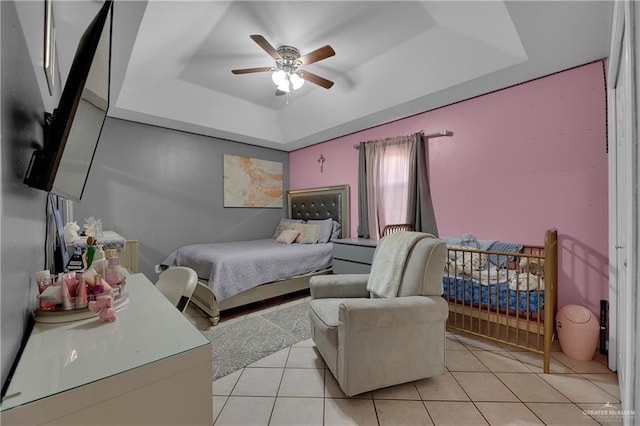 tiled bedroom with a tray ceiling and ceiling fan