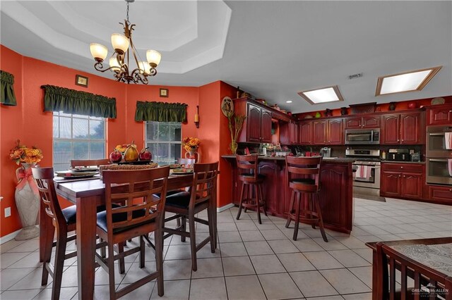 dining room with a tray ceiling, light tile patterned floors, and a notable chandelier