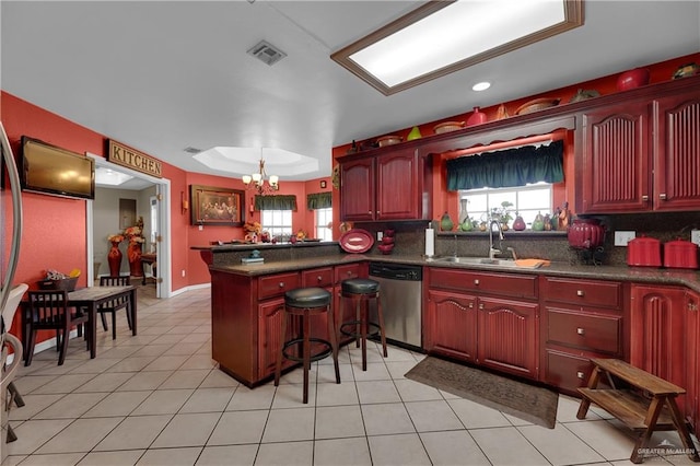 kitchen featuring kitchen peninsula, sink, pendant lighting, a notable chandelier, and dishwasher