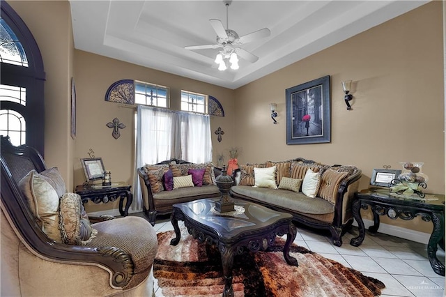 living room featuring light tile patterned floors, a raised ceiling, and ceiling fan