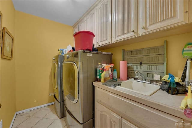 laundry area featuring cabinets, light tile patterned floors, washing machine and dryer, and sink