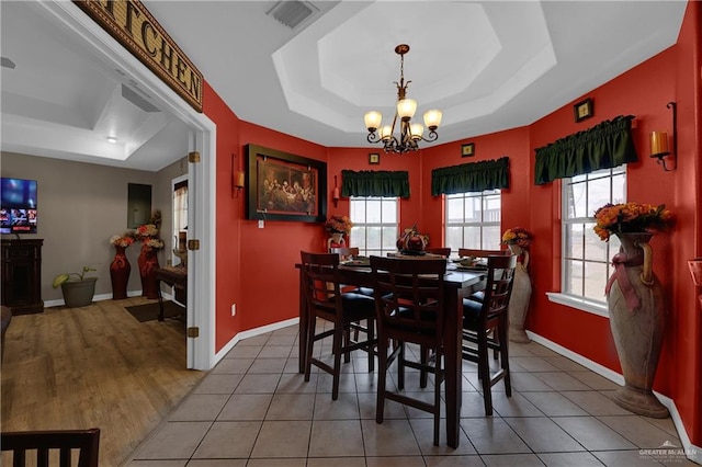 dining space featuring a chandelier, a tray ceiling, and a healthy amount of sunlight