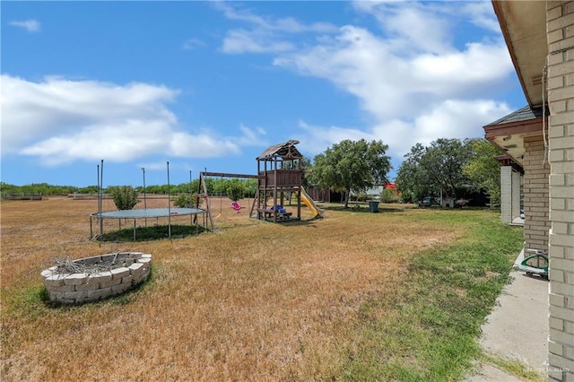 view of yard featuring a playground, a fire pit, and a trampoline