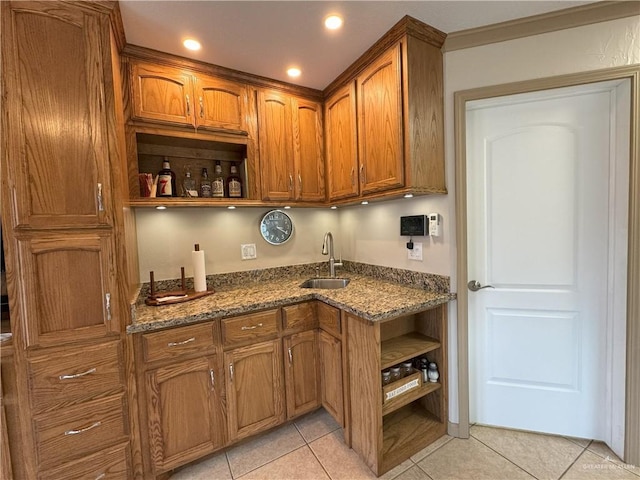 kitchen featuring light tile patterned floors, a sink, dark stone counters, open shelves, and brown cabinetry