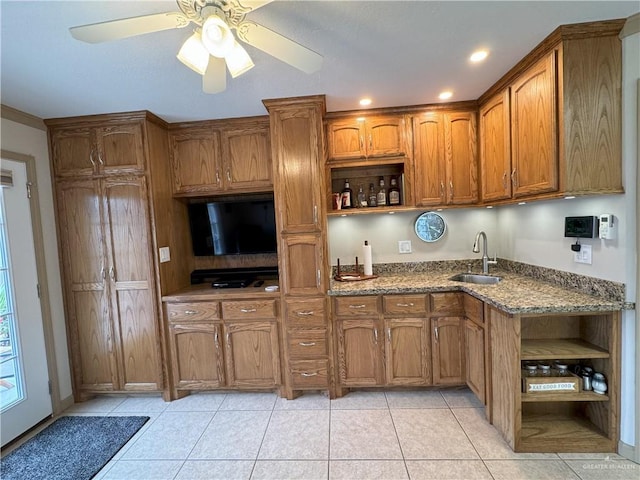 kitchen with brown cabinets, open shelves, light tile patterned flooring, a sink, and dark stone counters