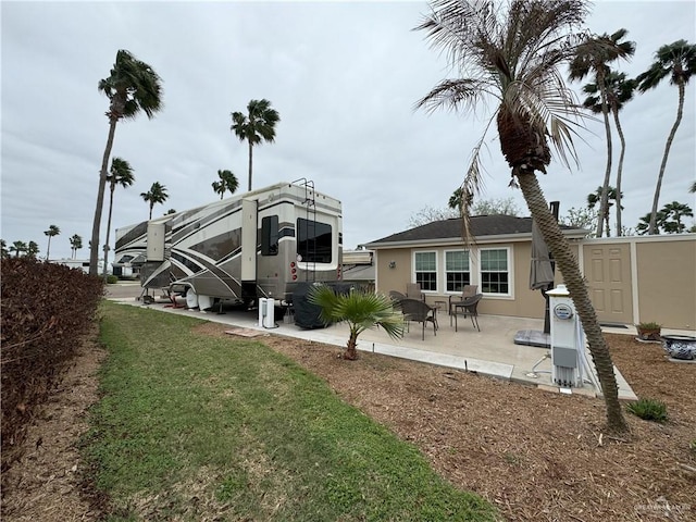 back of house featuring a yard, a patio area, and stucco siding